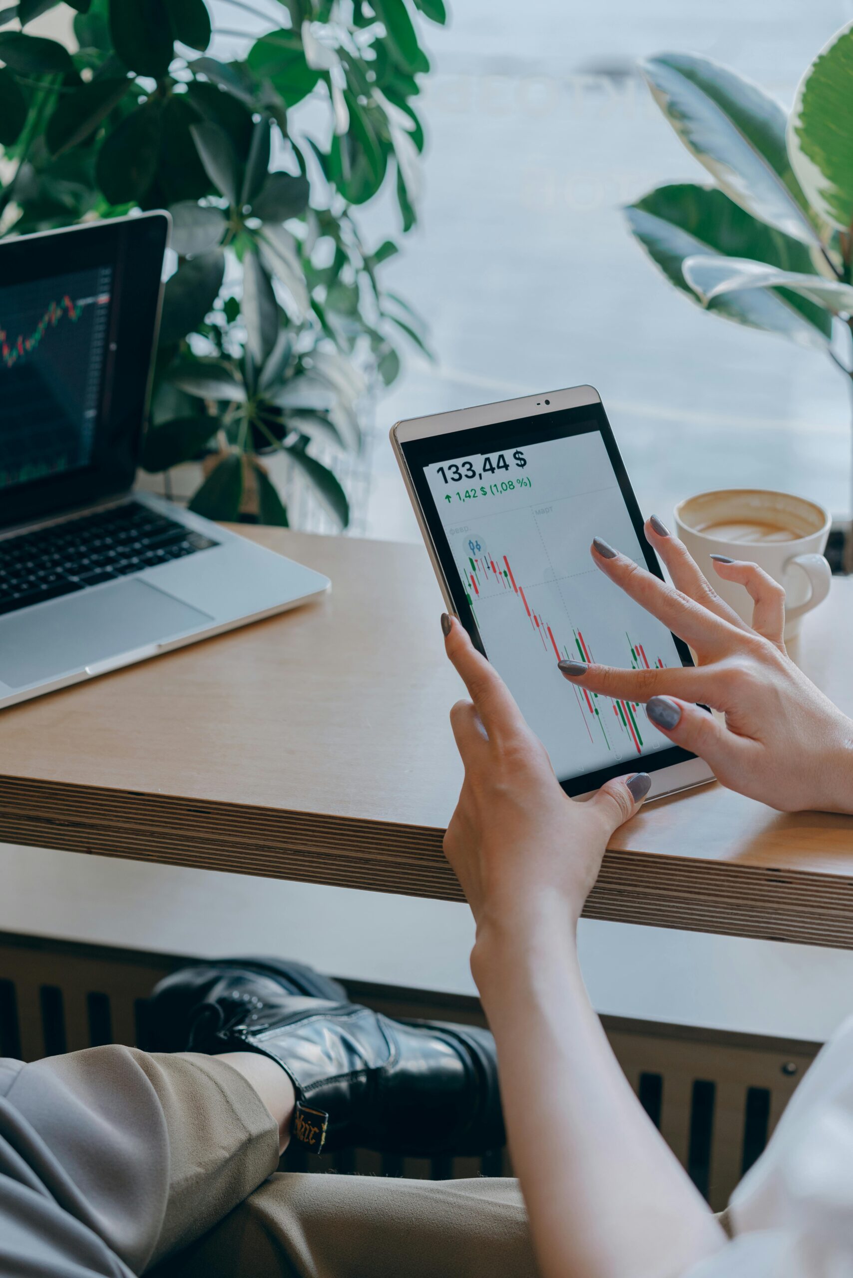 Close-up of hands using a tablet for stock market analysis in a modern office setting.