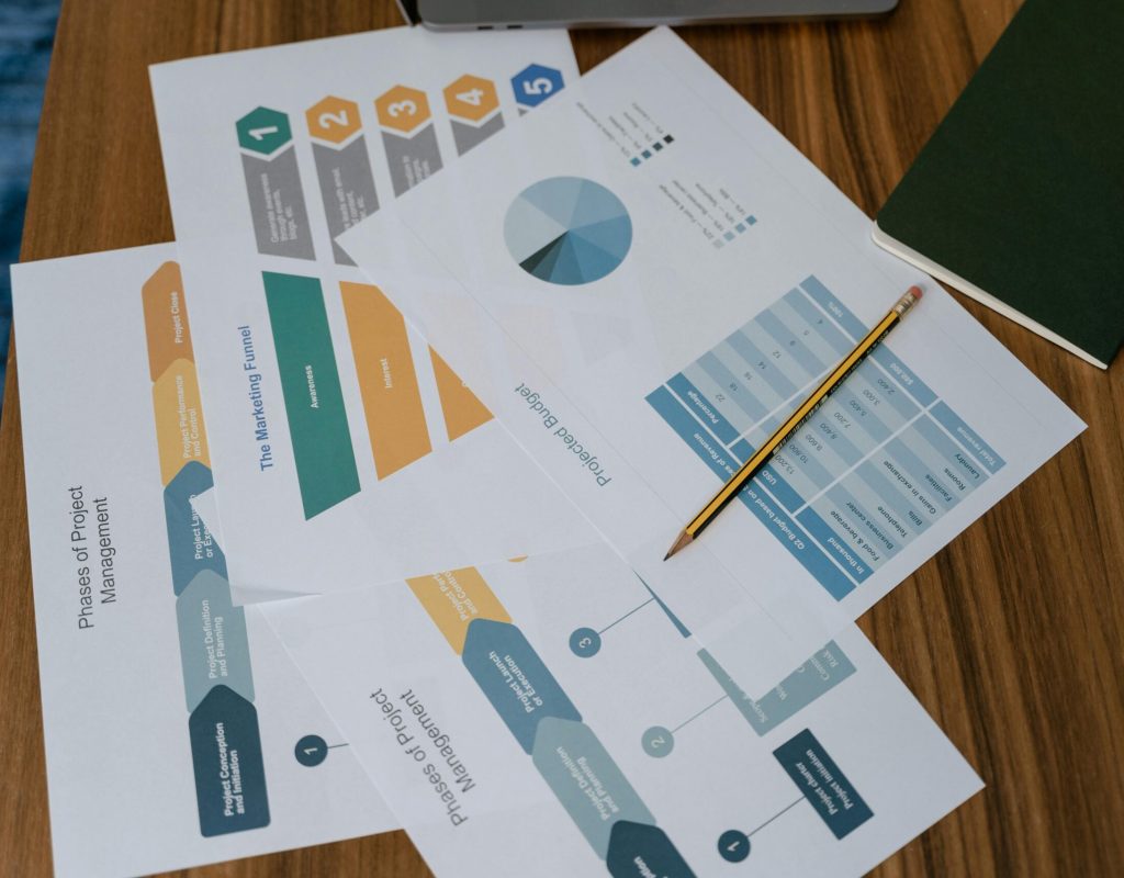Overhead view of project management documents and charts on a desk with a pencil.