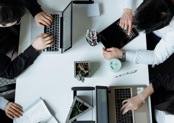 A diverse team working together in a modern office setting, focusing on laptops and collaboration.