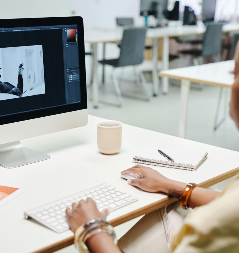 A woman using a computer for image editing in a bright, modern office setting.